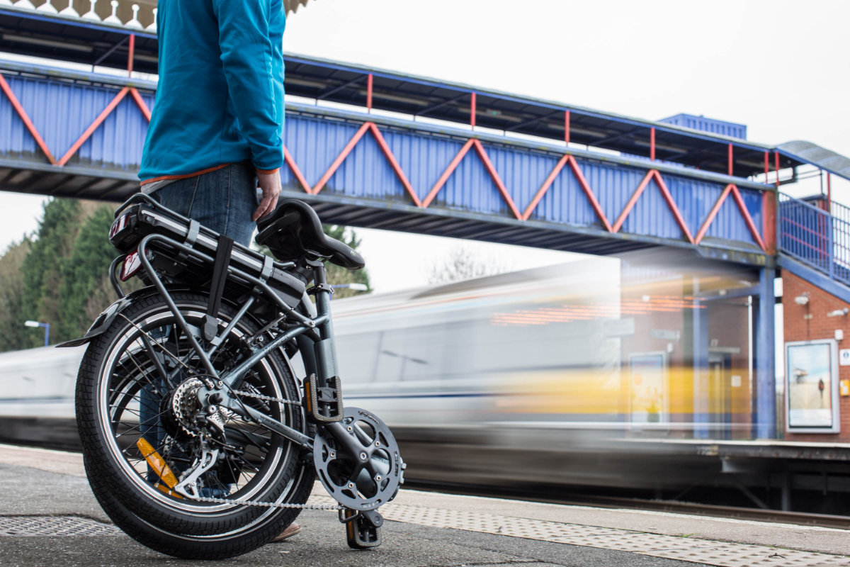 Man with a foldable bicycle at a train station